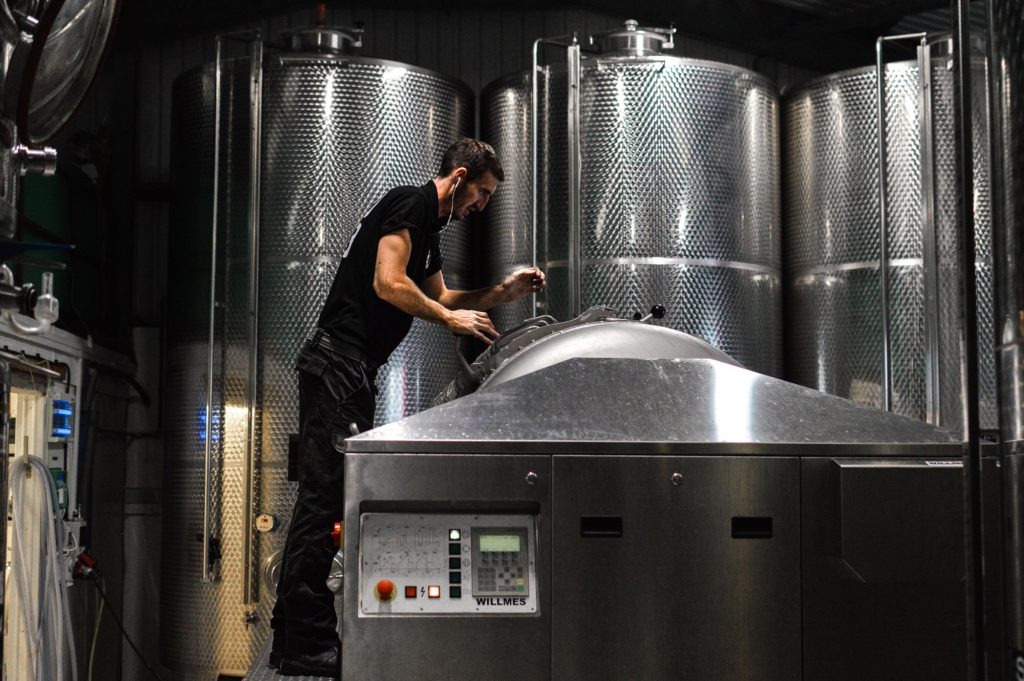 Man in a brewery standing over a brewing tank