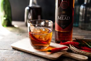 Mead in a glass with a paring knife and chillis