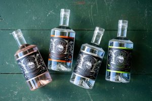 Bottles of LBW Gin on a green wood backdrop